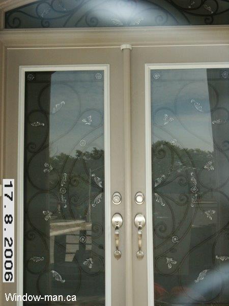 Double insulated front entry doors. Sand color. Full wrought iron glass door inserts. round top arch head transom with entry doors inserts. Custom wrought iron glass inserts